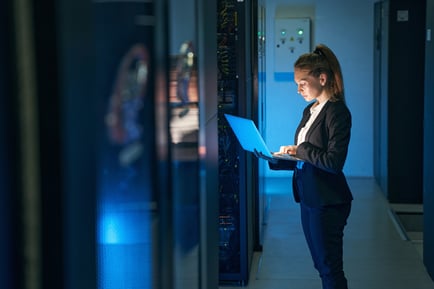 Woman Working on Laptop in Server Room